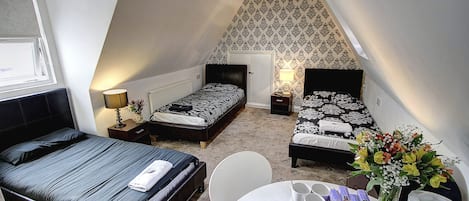 Ein Schlafzimmer mit zwei Betten, einem Esstisch und einer kleinen Küchenzeile.