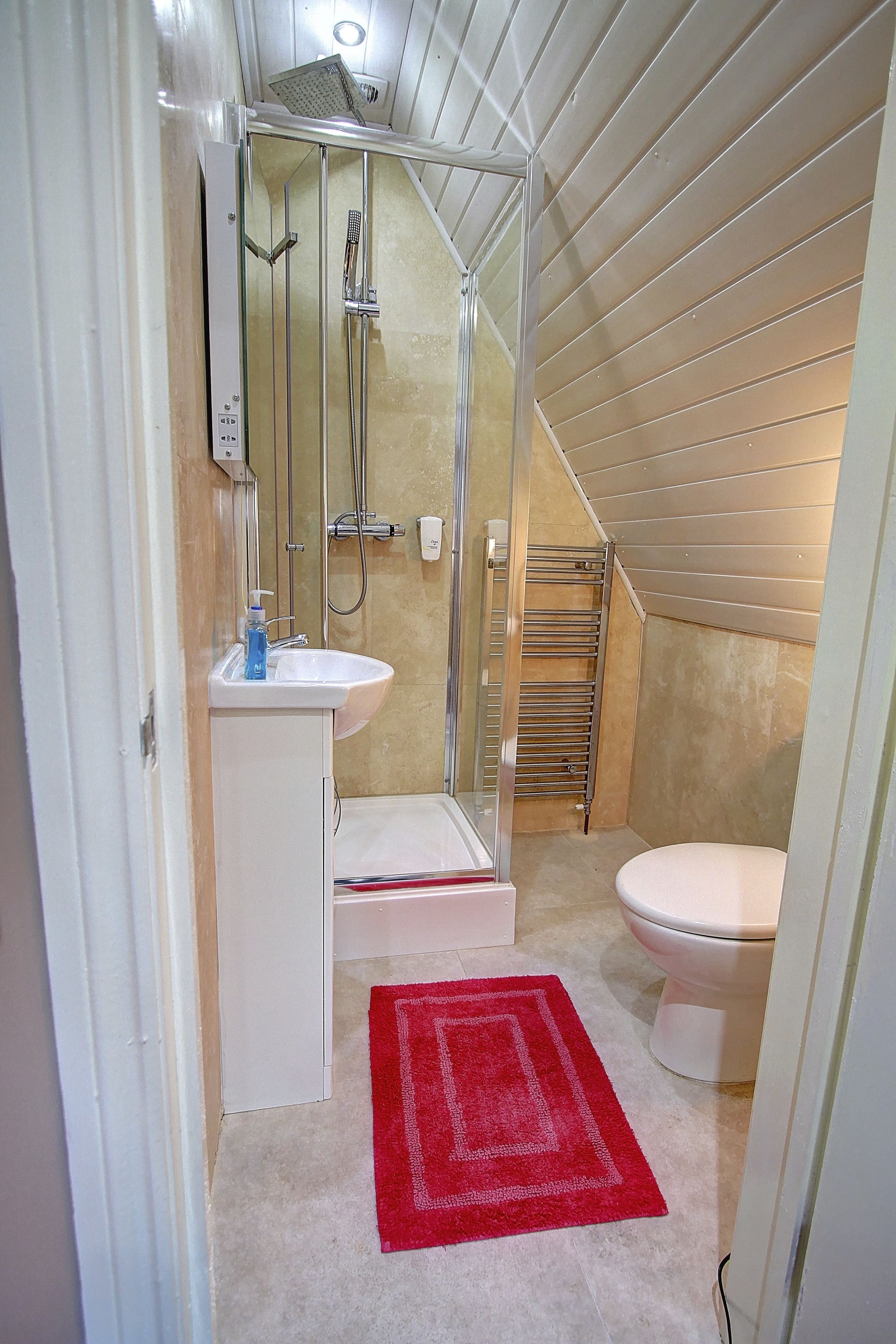 A compact bathroom with a shower, sink, and toilet.