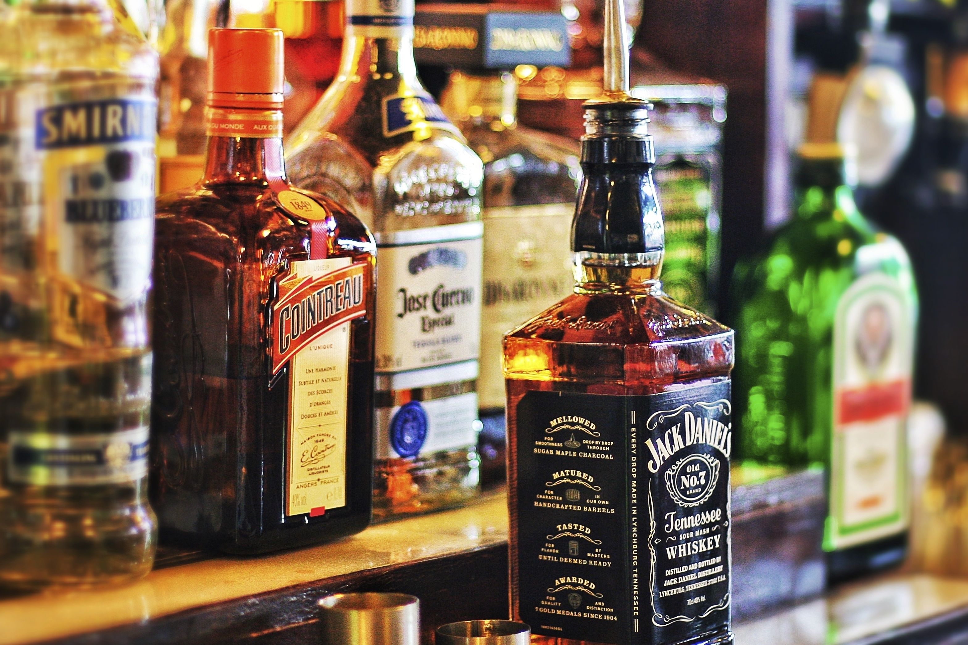 A variety of liquor bottles on a bar shelf.