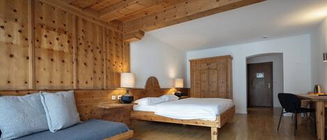 Una habitación tipo cabaña de madera con una cama, un sofá, un escritorio y una silla.