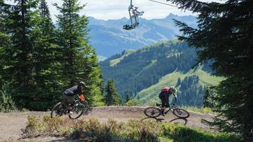 Zwei Mountainbiker auf einem unbefestigten Weg vor einer Bergkulisse.