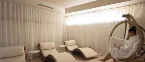 Un cuarto de spa con una silla de masaje, una silla reclinable y un sillón colgante de madera.