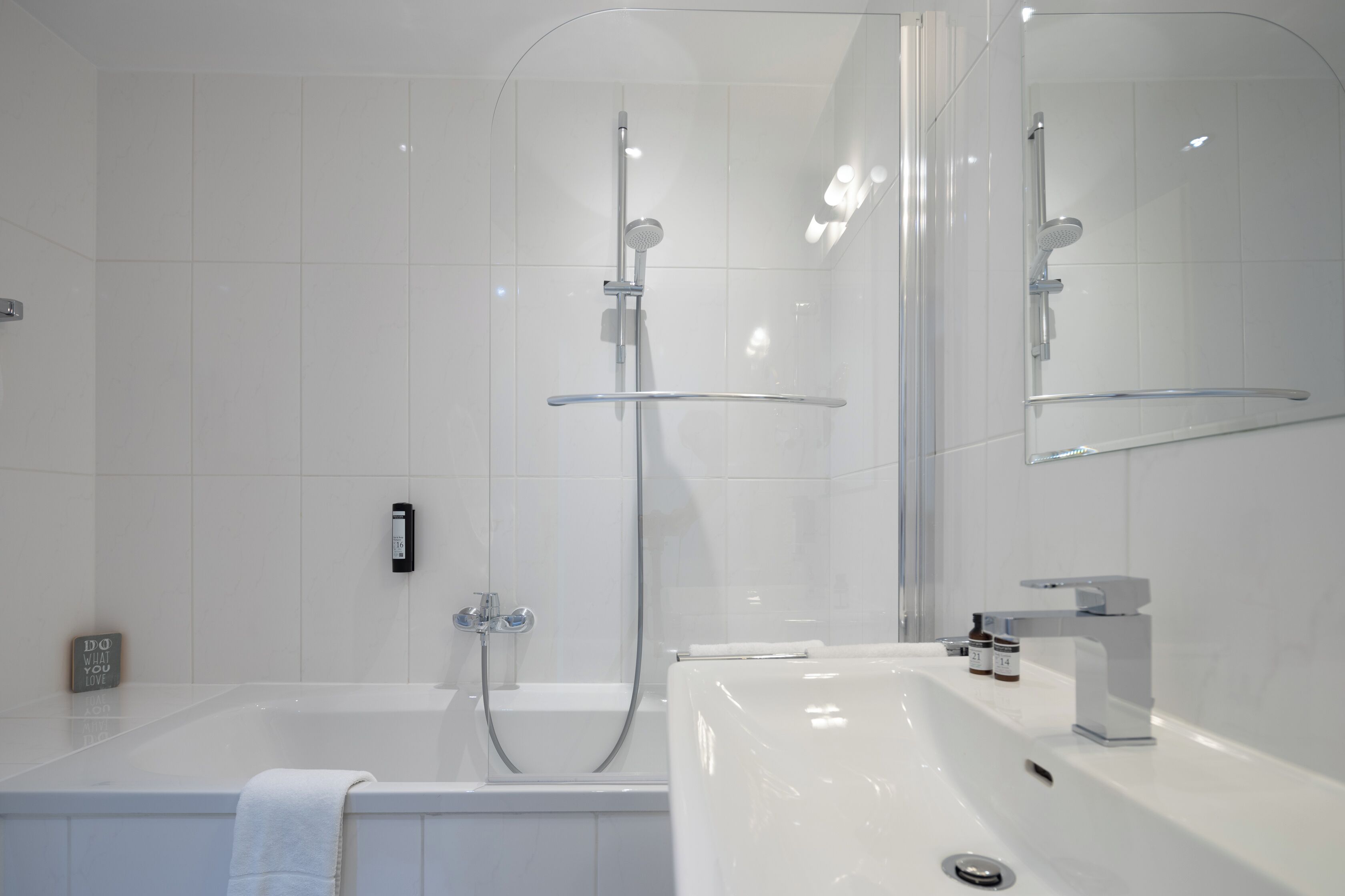 A modern bathroom with a bathtub, a shower, and a sink.