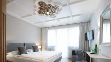 Habitación de hotel con una cama grande, un escritorio, una silla, un televisor y una ventana con cortinas.