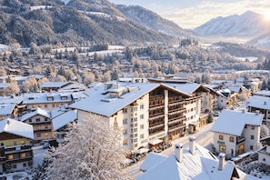 A snow-covered town with a prominent hotel featuring multiple balconies and a ski lift in the background. - Q Hotel Maria Theresia (Kitzbuhel)