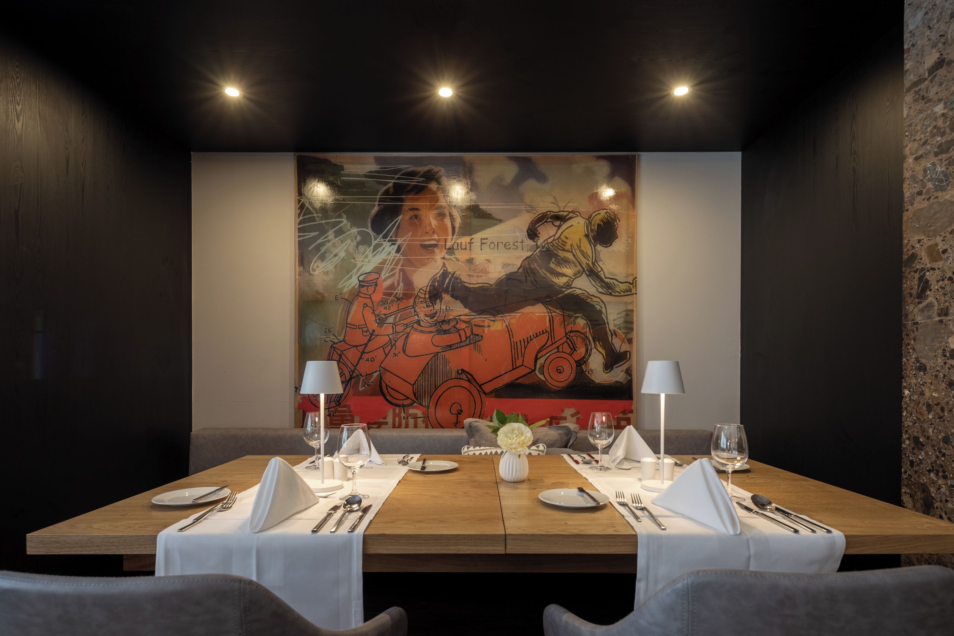 Een vergaderruimte met een lange tafel gedekt voor een vergadering, een groot abstract schilderij aan de muur en een stenen muur aan de zijkant.