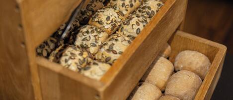 Una vitrina de madera con distintos tipos de pan, incluyendo bollos con semillas y hogazas redondas.