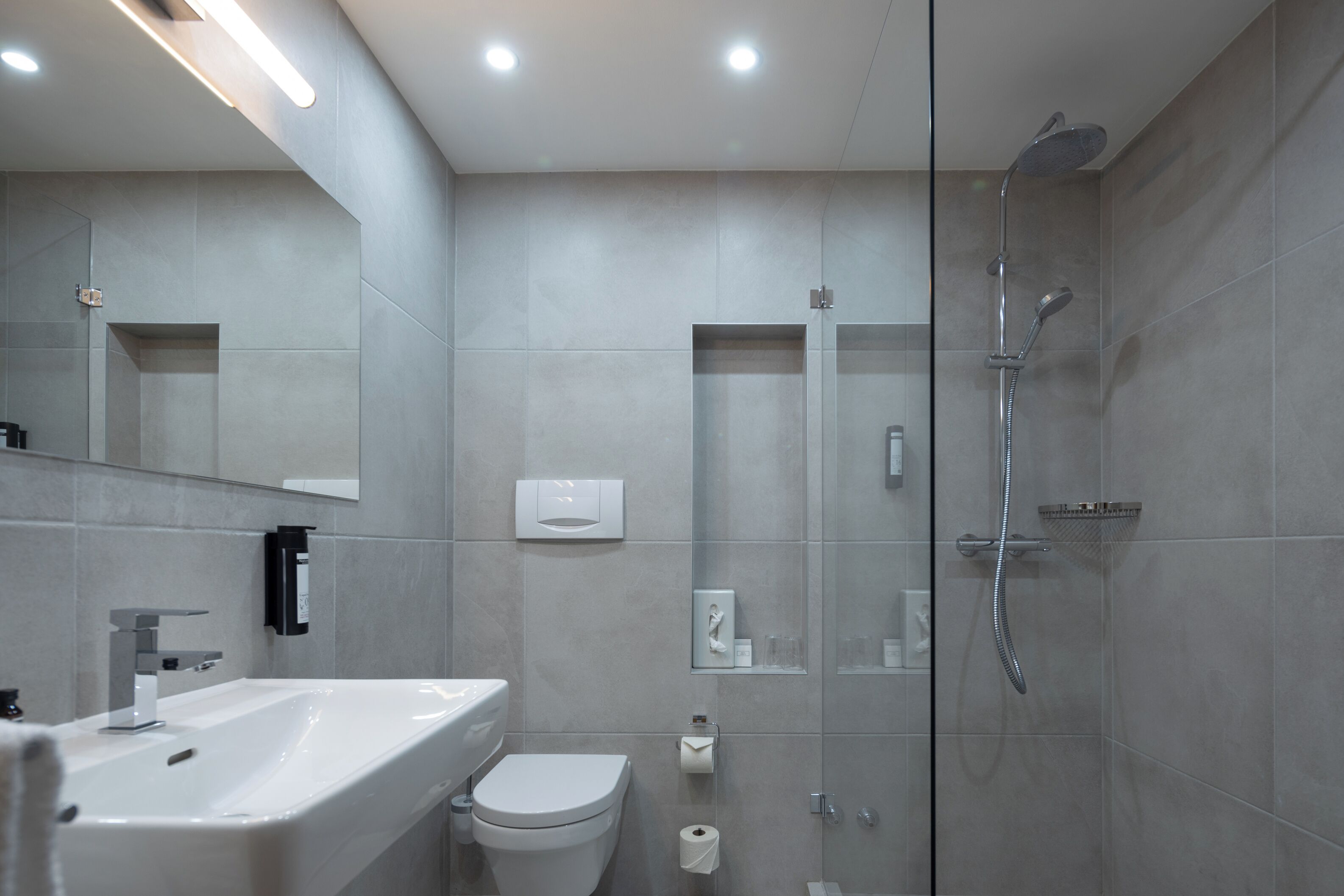 A modern bathroom with a sink, toilet, and shower.