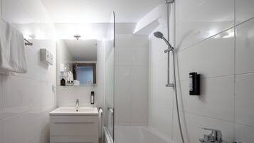 A modern bathroom with a glass shower enclosure, a white sink, and a mirror above it.