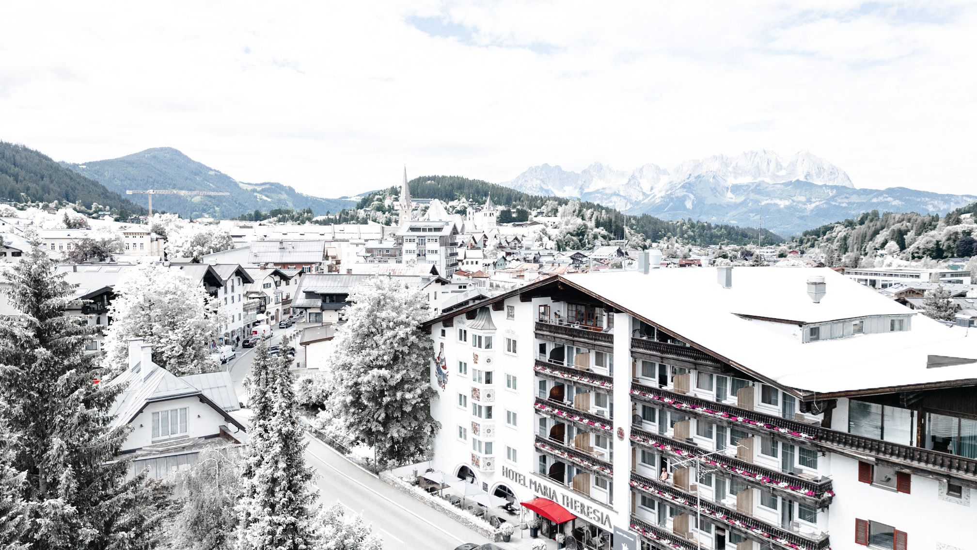 Un hotel con varios pisos, balcones y vistas a montañas nevadas.