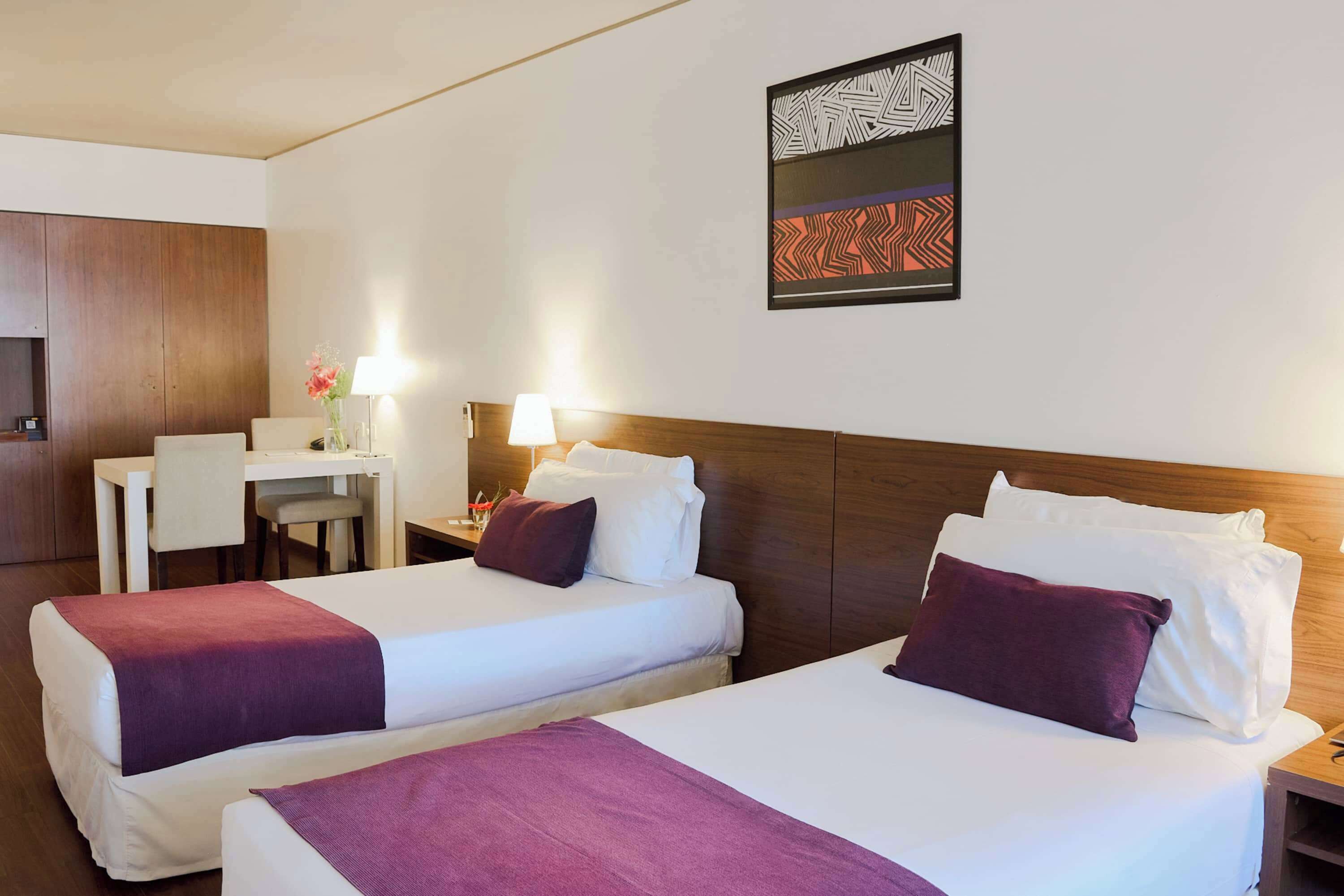 Ein Hotelzimmer mit zwei Betten, einem Schreibtisch und einem Stuhl.