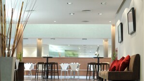 A modern hotel lobby with a reception desk, white and brown seating, and a polished floor. - Dazzler by Wyndham Buenos Aires Maipu (Buenos Aires)