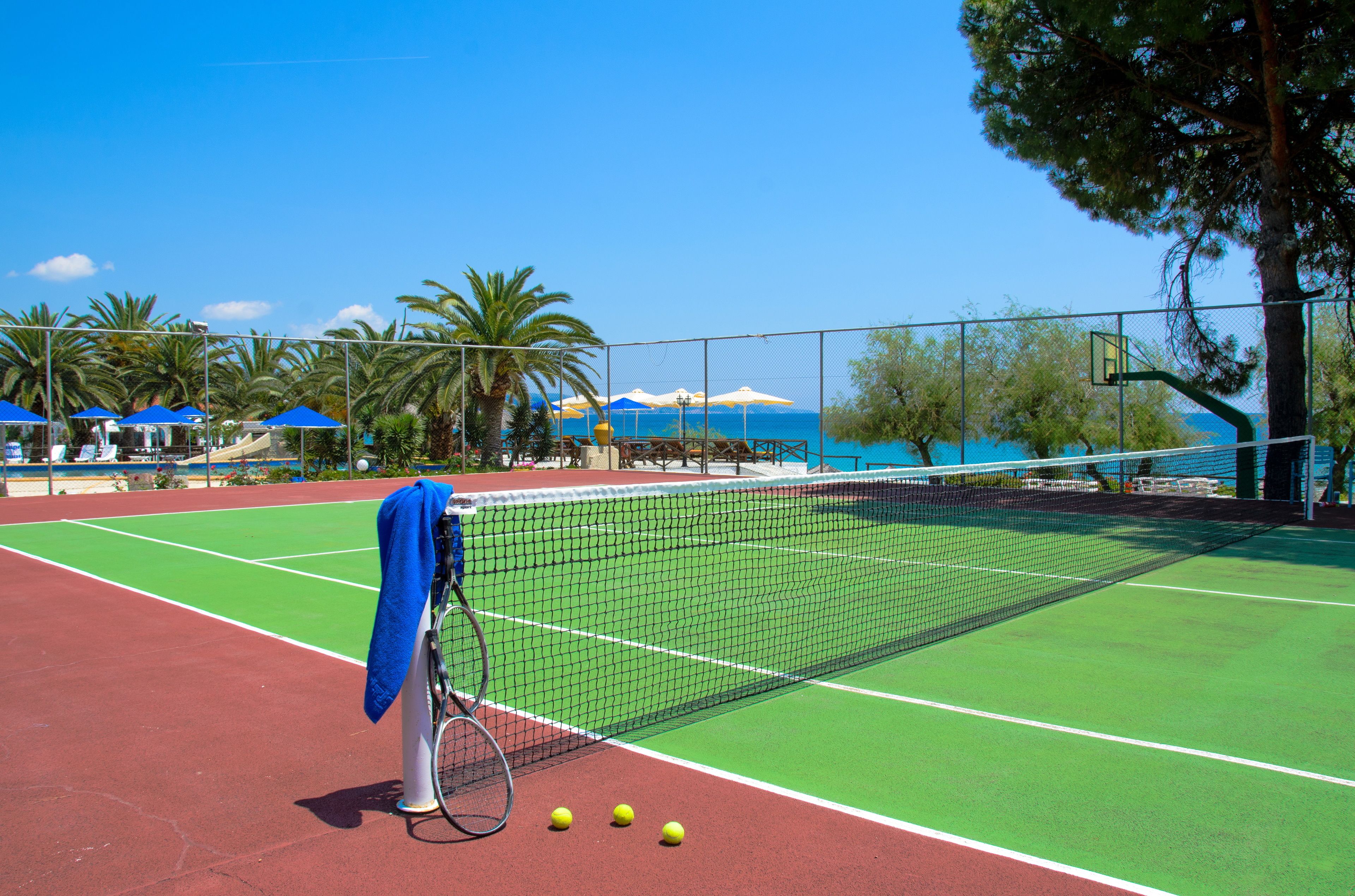 Una cancha de tenis con red, una raqueta y pelotas.