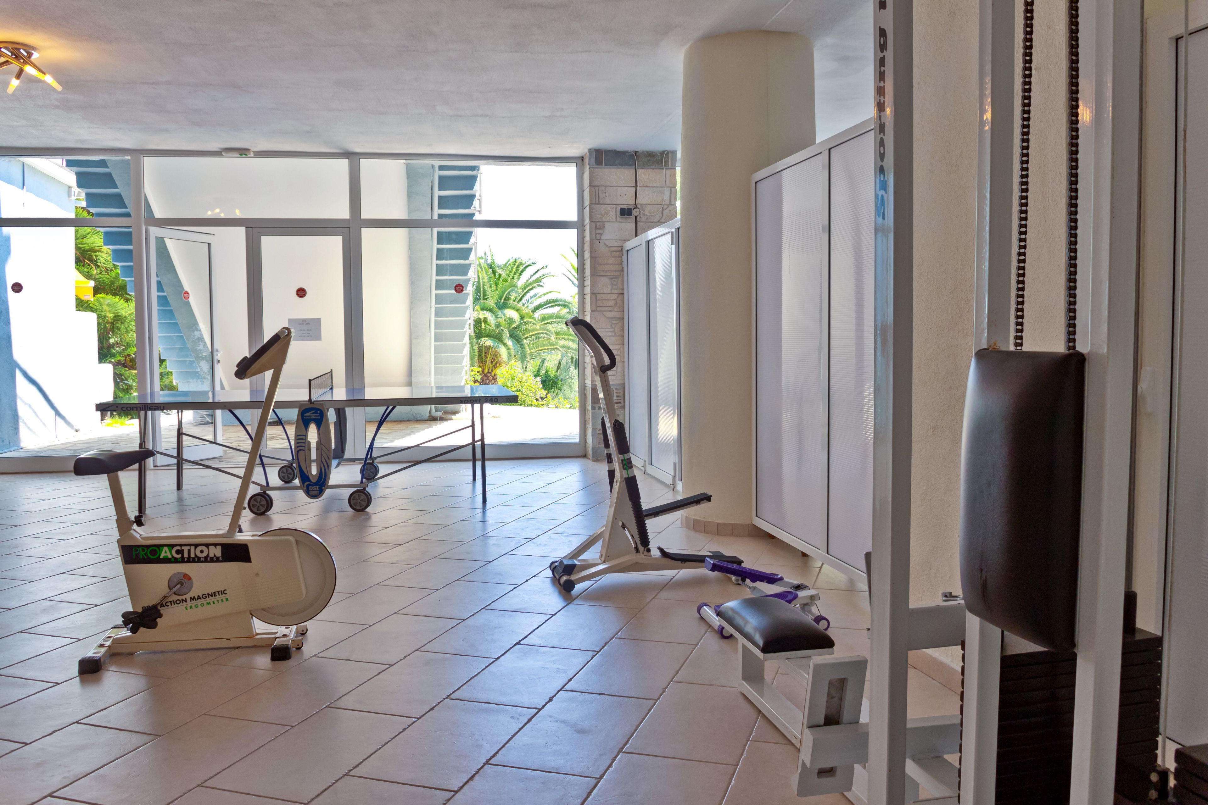 A gym with exercise equipment, a staircase, and a view of greenery outside.