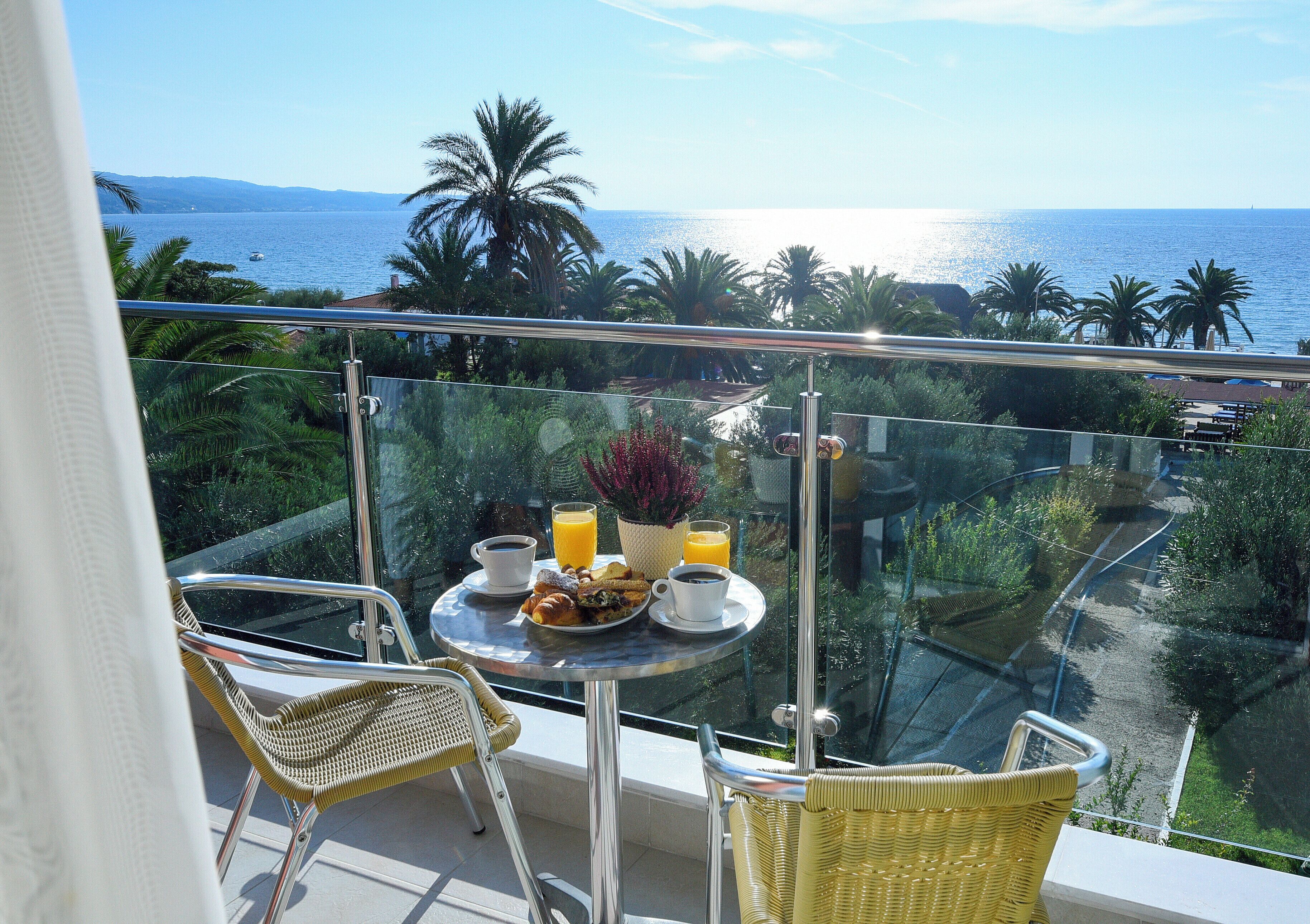 Un balcone con un tavolo apparecchiato per la colazione, con vista sulla costa.