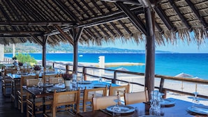 Un restaurante con mesas dispuestas para comer, con vistas a una playa y al mar.