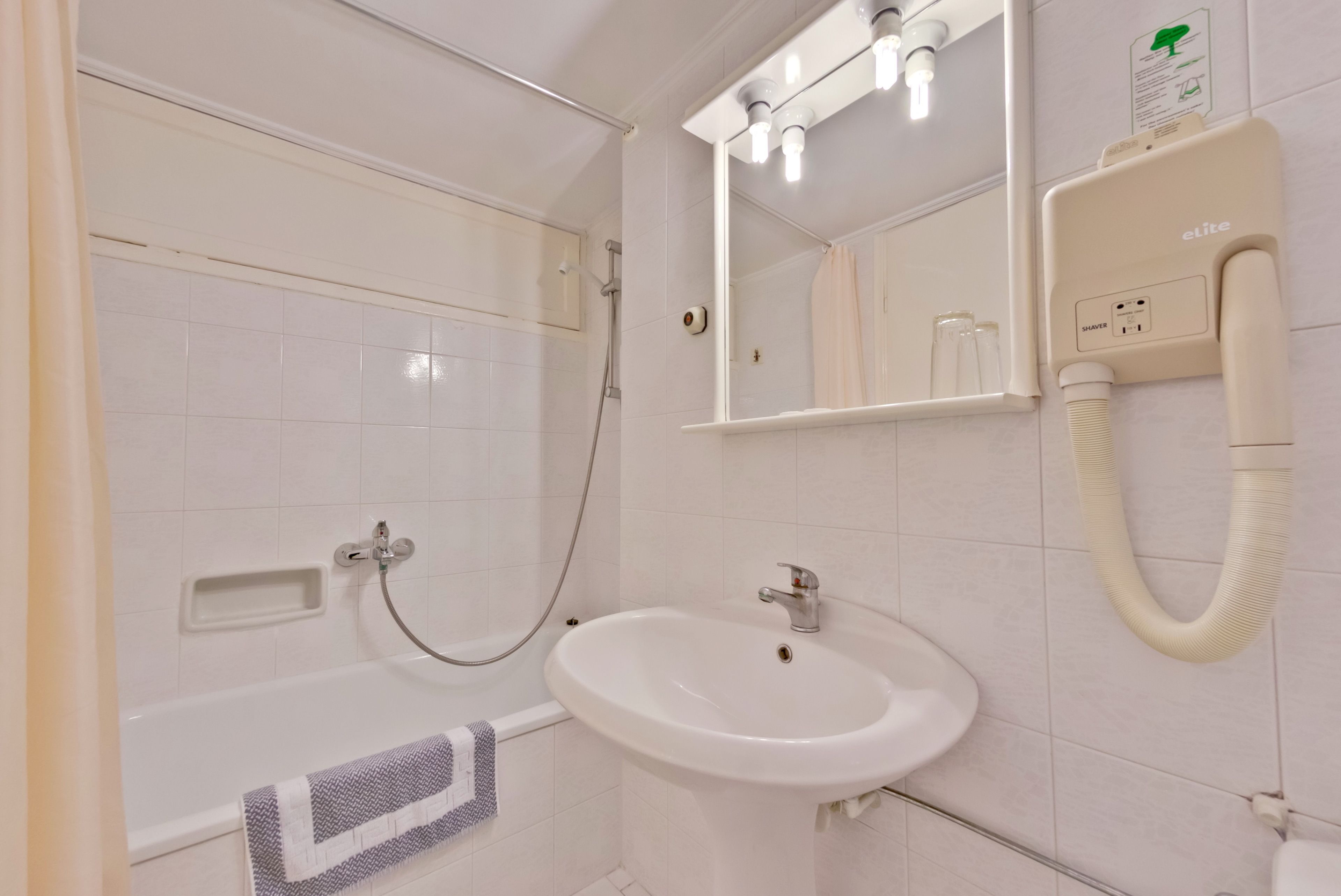 A bathroom with a bathtub, sink, and mirror.