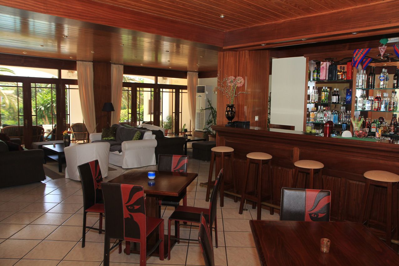 A bar area with wooden furniture, a bar counter, and a variety of bottles.