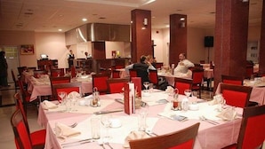 A restaurant with tables set for dining, red chairs, and a waiter attending to guests. - Car Hotel (Smederevo)