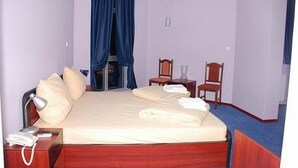 A hotel room with a bed, a desk with a lamp, a chair, and a window with curtains. - Car Hotel (Smederevo)