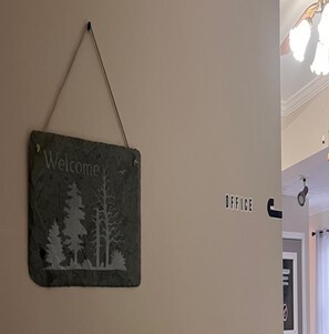 A welcome sign with a forest scene, a door labeled "OFFICE", and a ceiling light fixture.