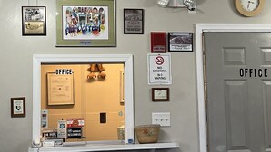 Una oficina con un cartel enmarcado, un reloj y un letrero de 'No Fumar'.