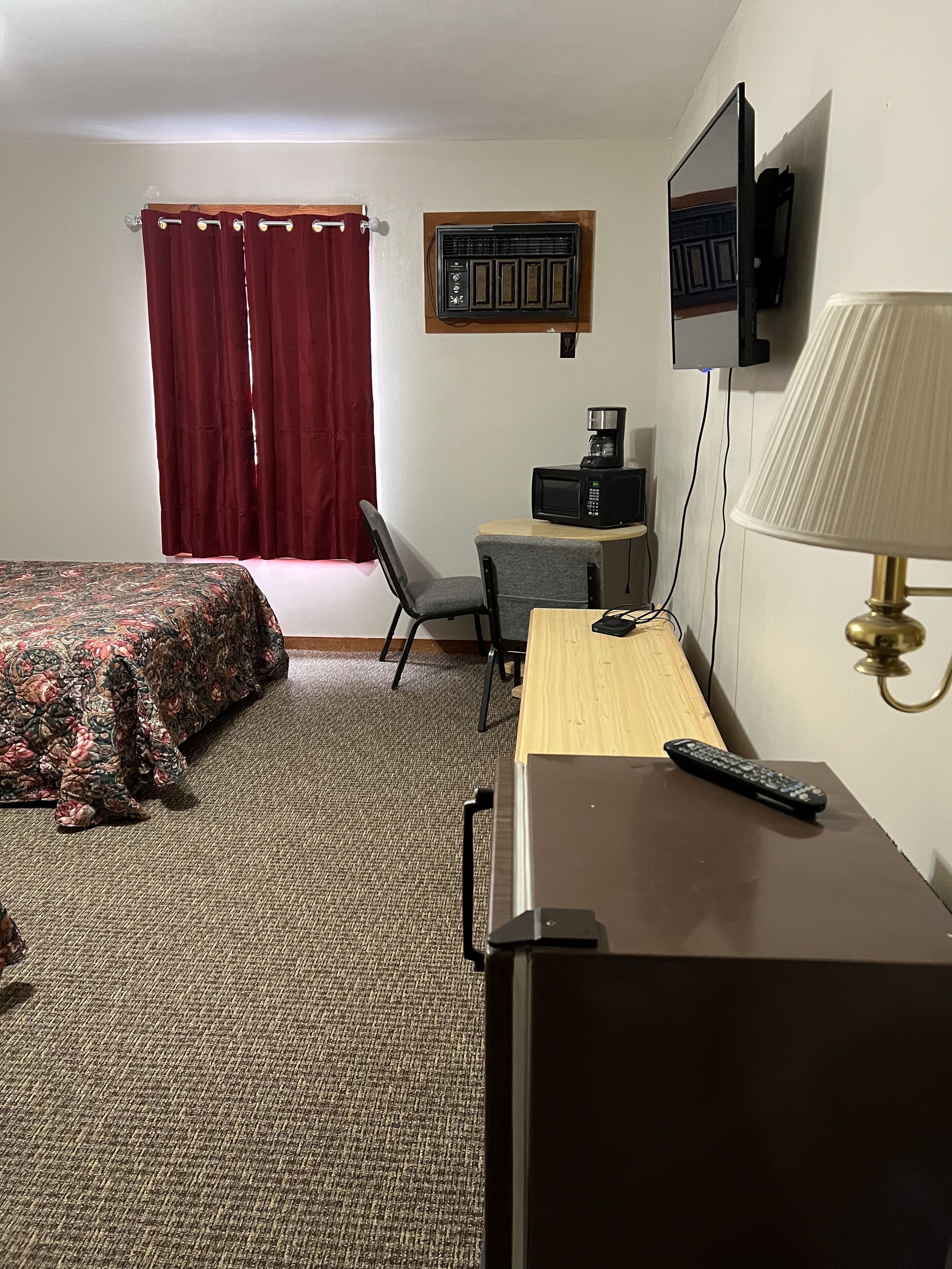 Ein Hotelzimmer mit einem Bett, einem Schreibtisch, einem Sessel, einem Fernseher und einer Lampe.