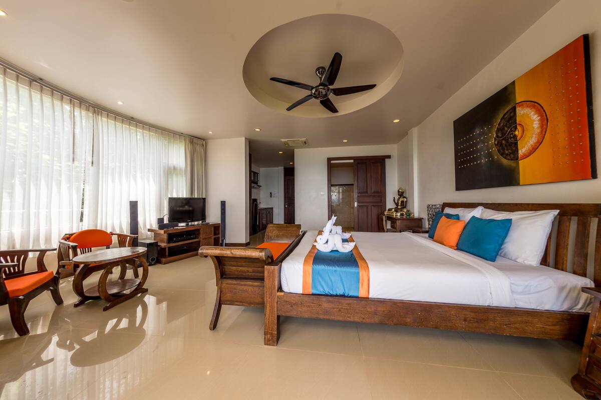 A hotel room with a bed, a TV, a desk, and a chair.