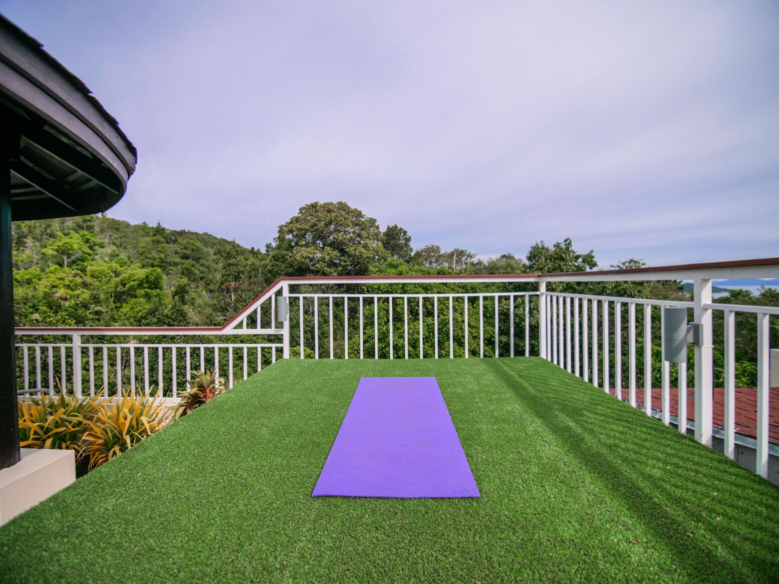 A balcony with artificial grass and a purple exercise mat.