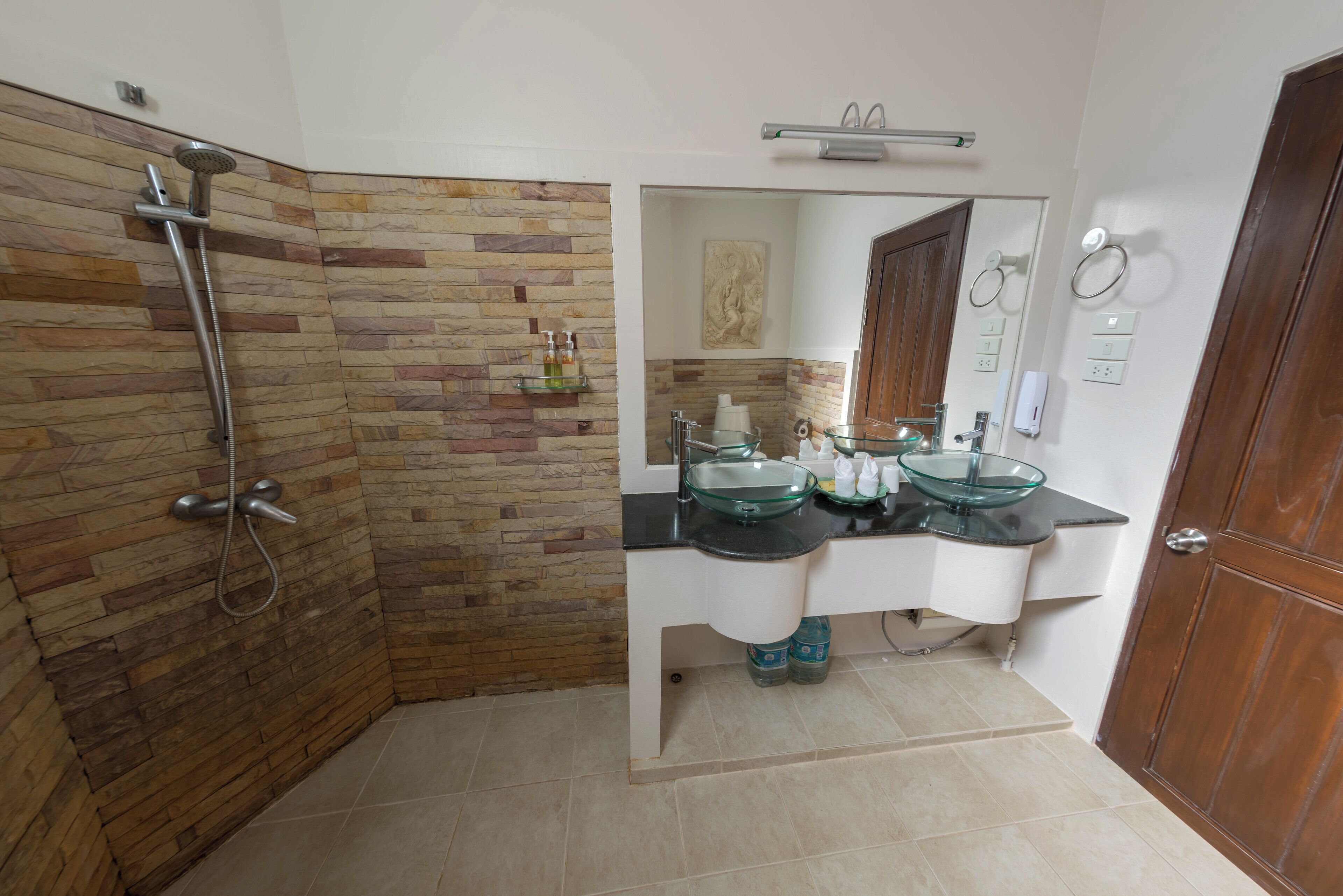 A bathroom with a shower, two sinks, a mirror, and a towel rack.