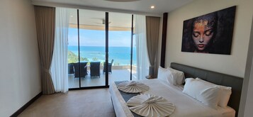 Habitación de hotel con una cama grande, vista al océano y un cuadro en la pared.