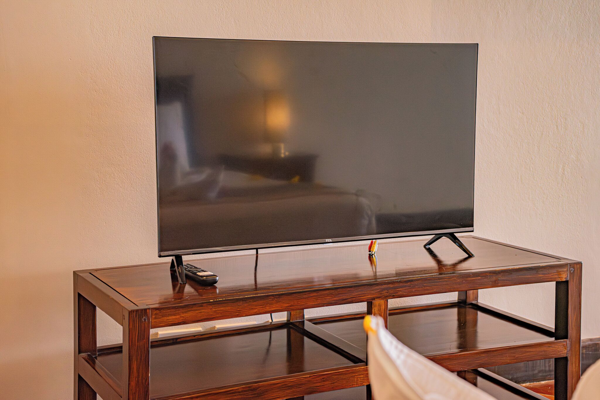 Un televisor de pantalla plana sobre un mueble de madera con un control remoto.