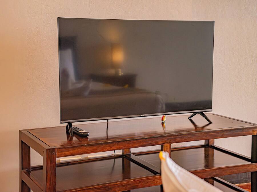 Un televisor de pantalla plana sobre un mueble de madera con un control remoto.
