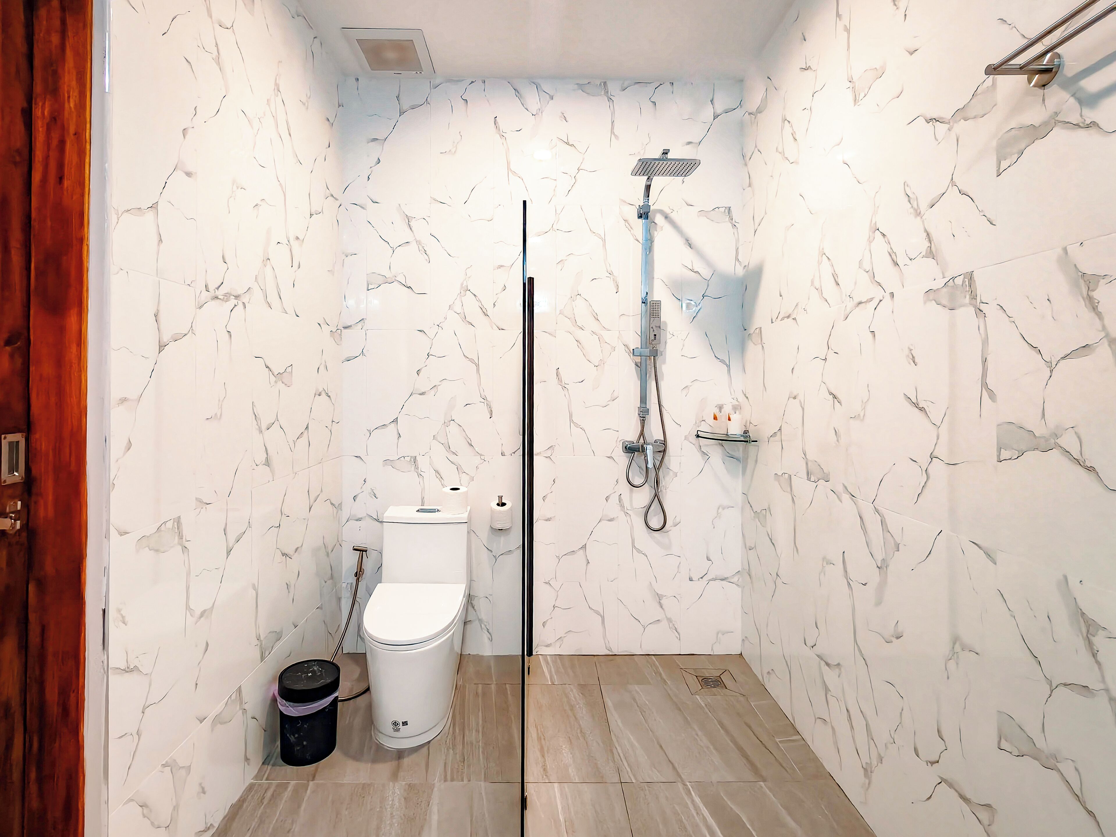 Un baño pequeño con inodoro, cubo de basura y ducha.