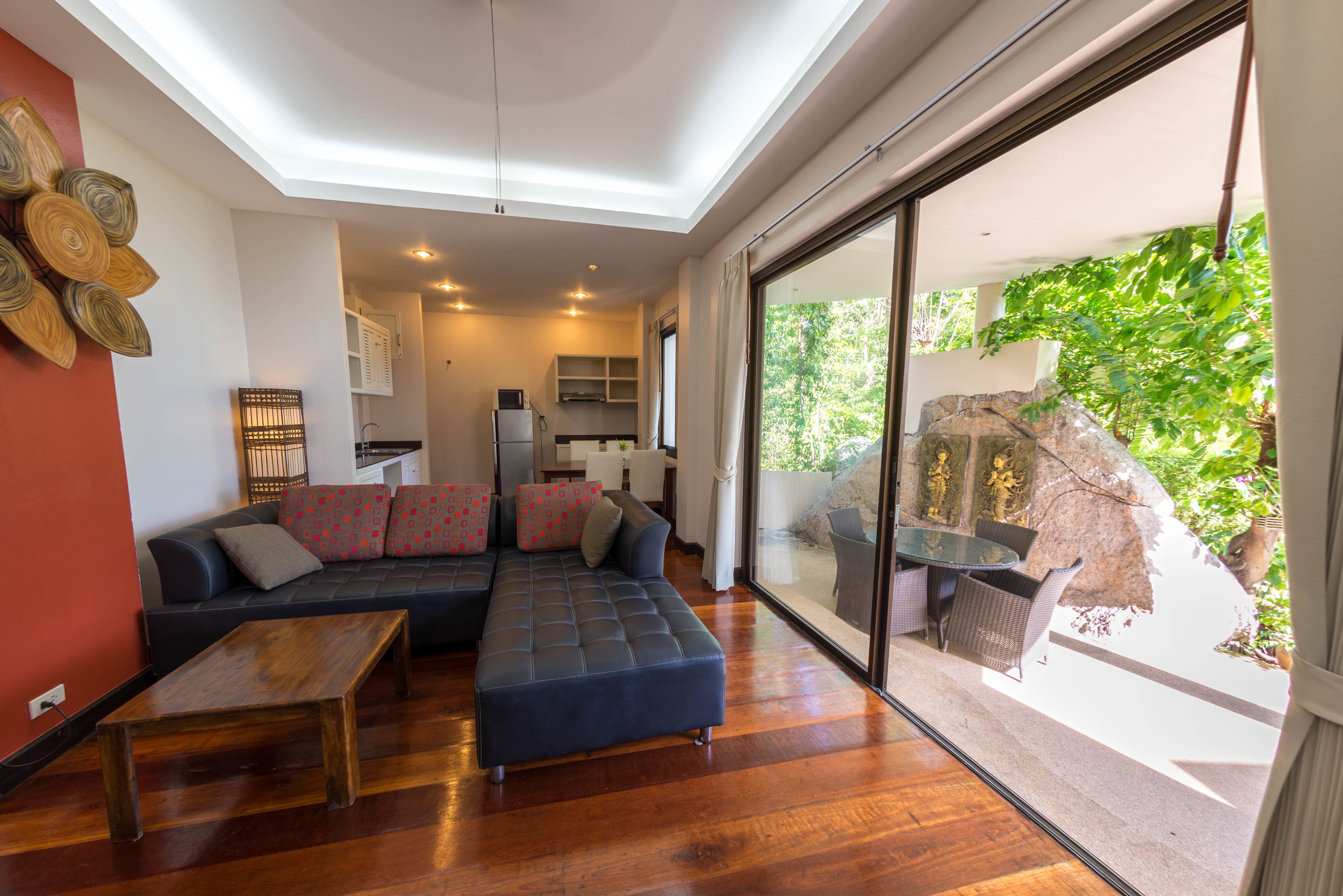 A modern living room with a sectional sofa, a wooden coffee table, and a dining area with wicker chairs.