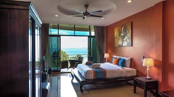 A hotel room with a bed, bedside lamps, a ceiling fan, a large window with a view, and a painting on the wall.