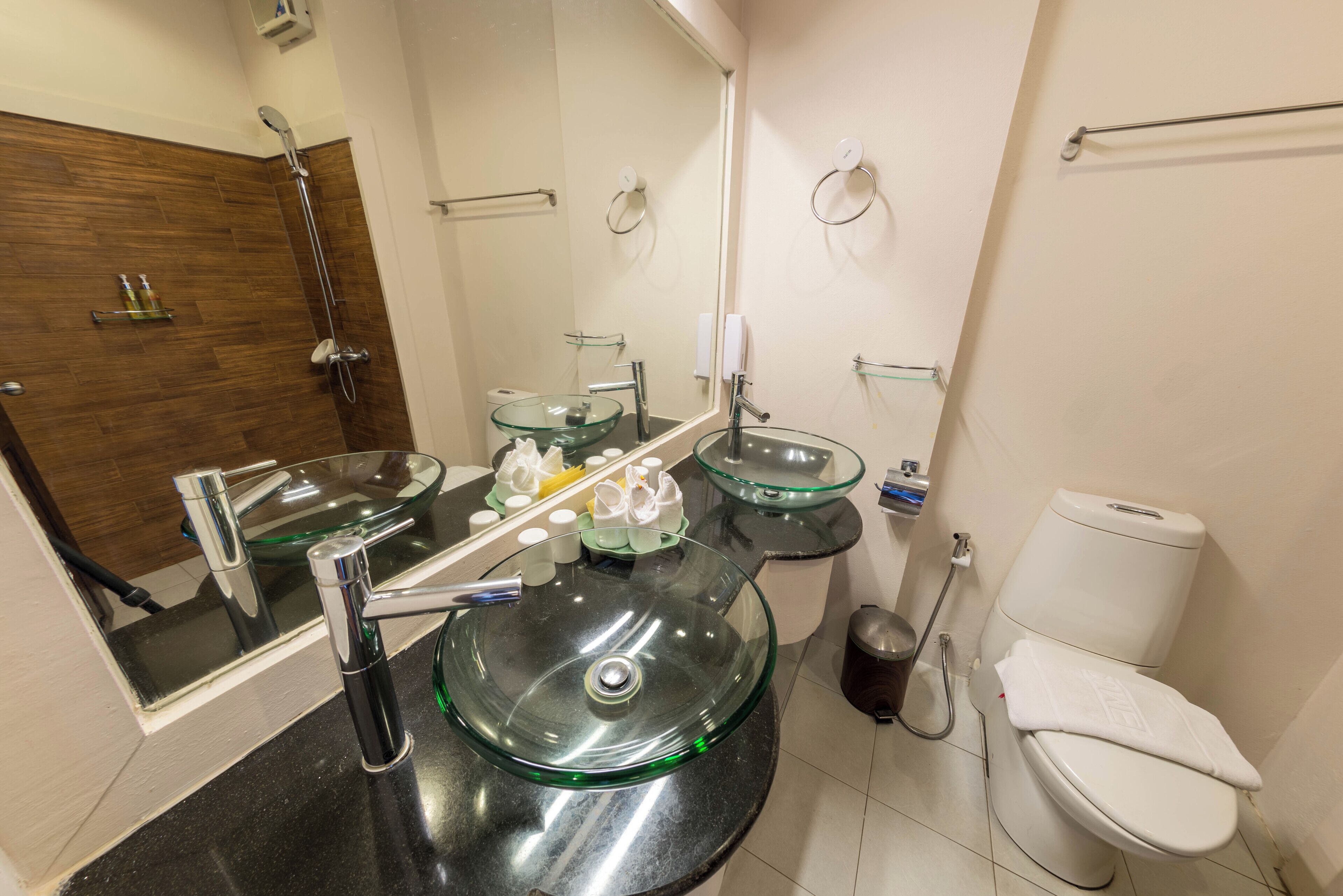 A modern bathroom with a glass sink, a toilet, and a shower.