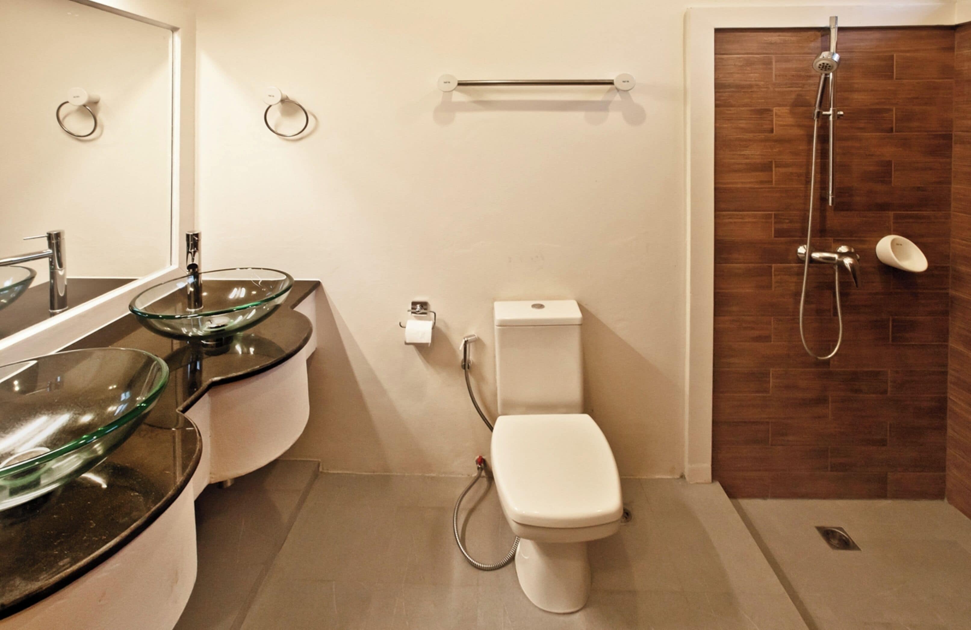 A modern bathroom with a glass bowl sink, a toilet, and a shower.
