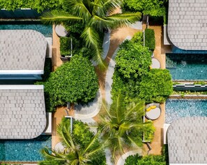 An aerial view of a resort with multiple swimming pools, lush greenery, and palm trees. - Avani+ Samui Resort (Koh Samui)