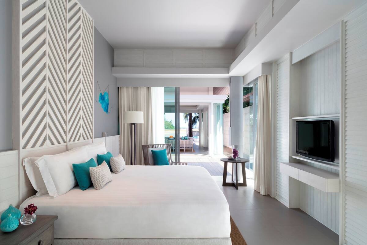 Una habitación de hotel moderna con una cama grande, televisión, escritorio y vistas al exterior.