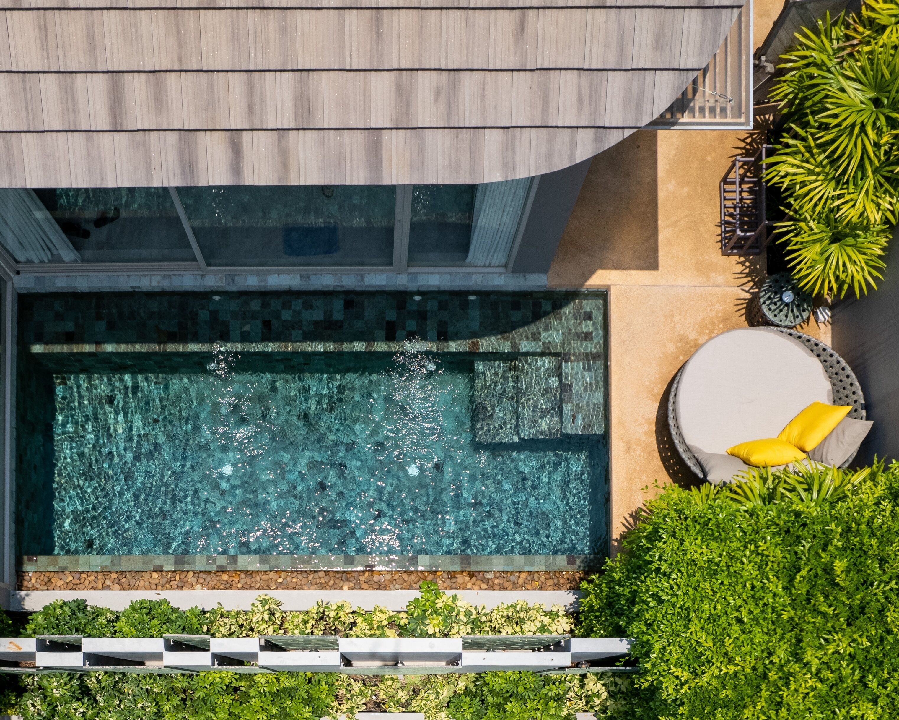 Una piscina en la azotea con vistas despejadas del cielo, rodeada de exuberante vegetación y un moderno espacio de estar al aire libre.