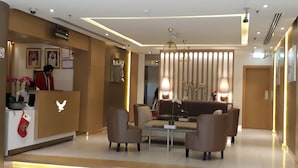 A modern hotel lobby with a reception desk, seating area, and decorative lighting. - Royal Falcon Hotel (Dubai)