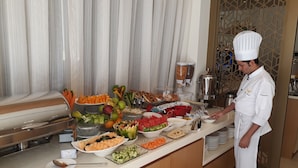 A buffet setup with various food items and a chef in uniform. - Royal Falcon Hotel (Dubai)
