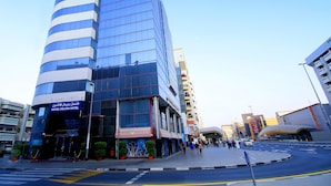 A modern hotel with a curved facade, multiple floors, and a prominent sign at the top. - Royal Falcon Hotel (Dubai)