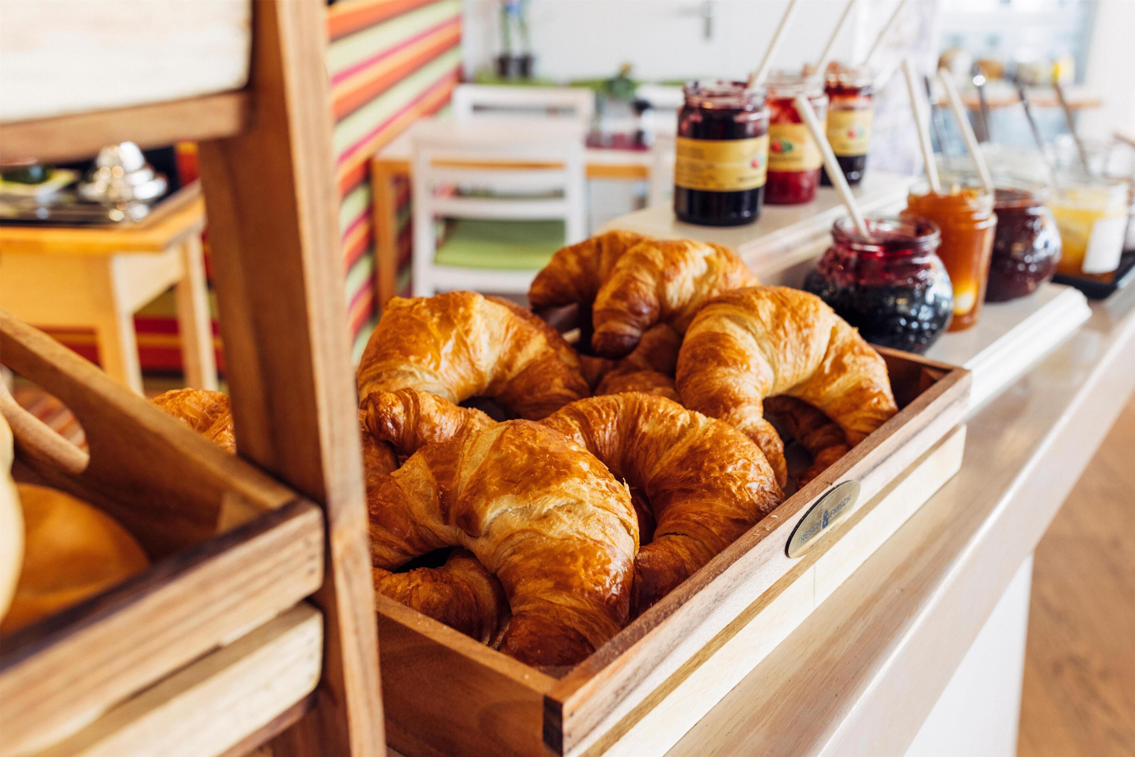 Eine Hollauslage mit Croissants und Marmeladengläsern.