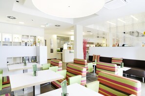 Un restaurante moderno con asientos a rayas, un área de recepción y una barra.