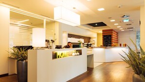 A modern reception area with a wooden floor, a reception desk labeled "HOME," and a bar area in the background. - harry’s home Linz-Urfahr hotel & apartments (Linz)