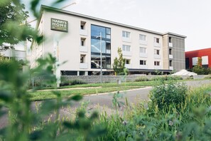 Un edificio moderno de hotel con un letrero que dice "Harry's Home". Cuenta con un amplio frente de vidrio, varios balcones y una base de piedra.