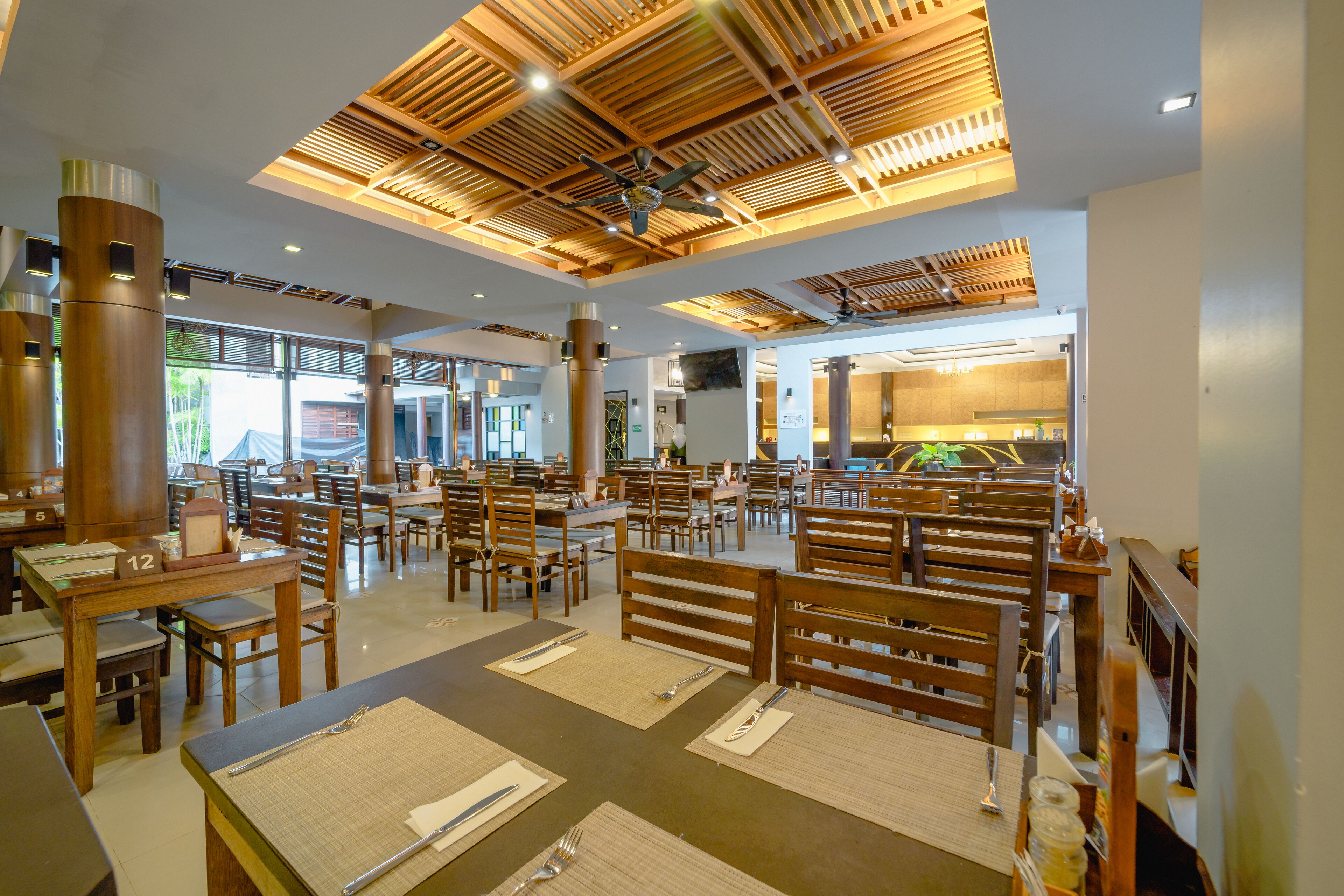 A spacious restaurant with wooden furniture, high ceilings with exposed beams, and a modern design.