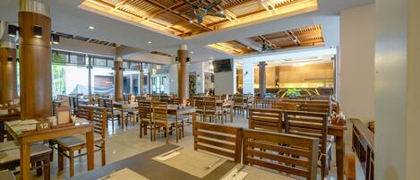 A spacious restaurant with wooden furniture, high ceilings with exposed beams, and a modern design.